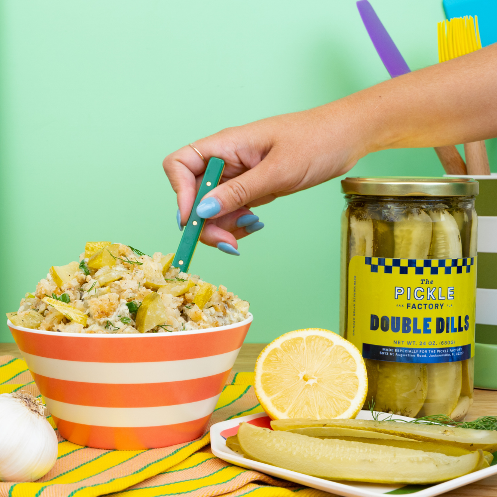 Crisp Tater Tot Pickle Salad in striped bowl, surrounded by Ayoh! Dill Pickle Mayo, Garlic & Friends seasoning, Double Dill pickles, and lemon slices.