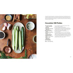Cucumber dill pickles on a wooden table with ingredients and a recipe.
