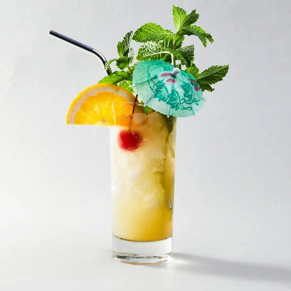 Cocktail with orange slice, cherry, and mint leaves on a white background