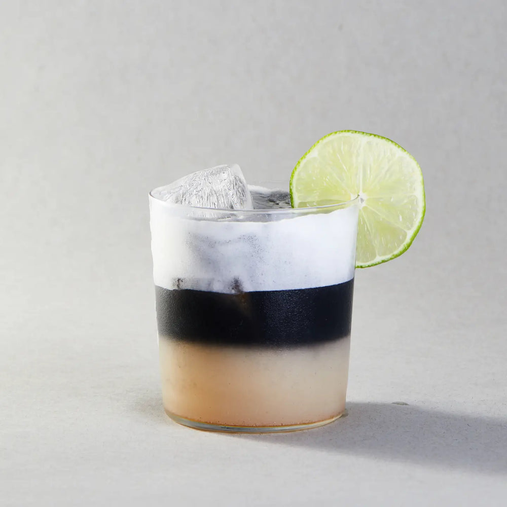 Cocktail with a lime wedge on a gray background