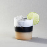 Cocktail with a lime wedge on a gray background