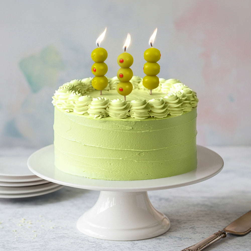 Green cake with olive candles on a white stand against a light background