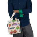 A person holding the Richard Scarry Things That Go canvas mini tote around there arm on a white background.