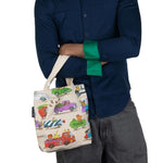A person holding the Richard Scarry Things That Go canvas mini tote around there arm on a white background.