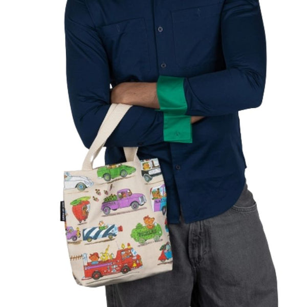 A person holding the Richard Scarry Things That Go canvas mini tote around there arm on a white background.