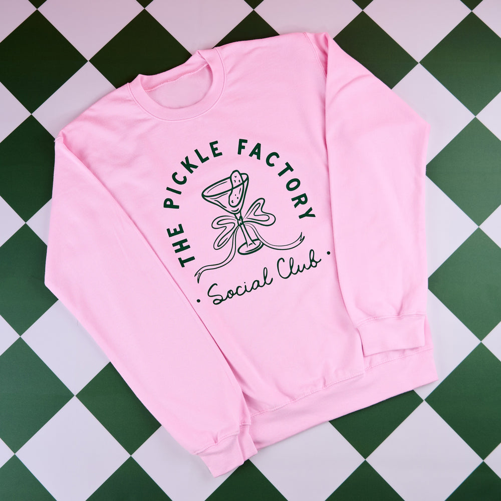 Pink sweatshirt with 'The Pickle Factory Social Club' design on a green and white checkered background
