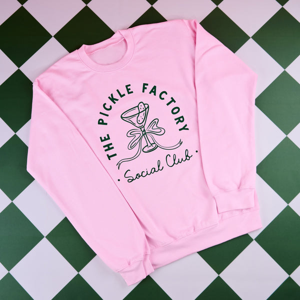 Pink sweatshirt with 'The Pickle Factory Social Club' design on a green and white checkered background