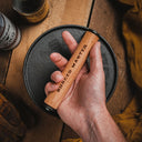 Hand holding a cast iron burger press labeled 'Burger Master' over a wooden surface.